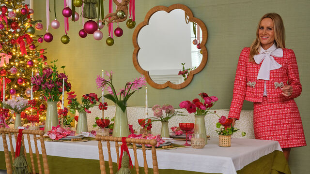 Women in red boucle outfit standing in dining room decorated for the holidays